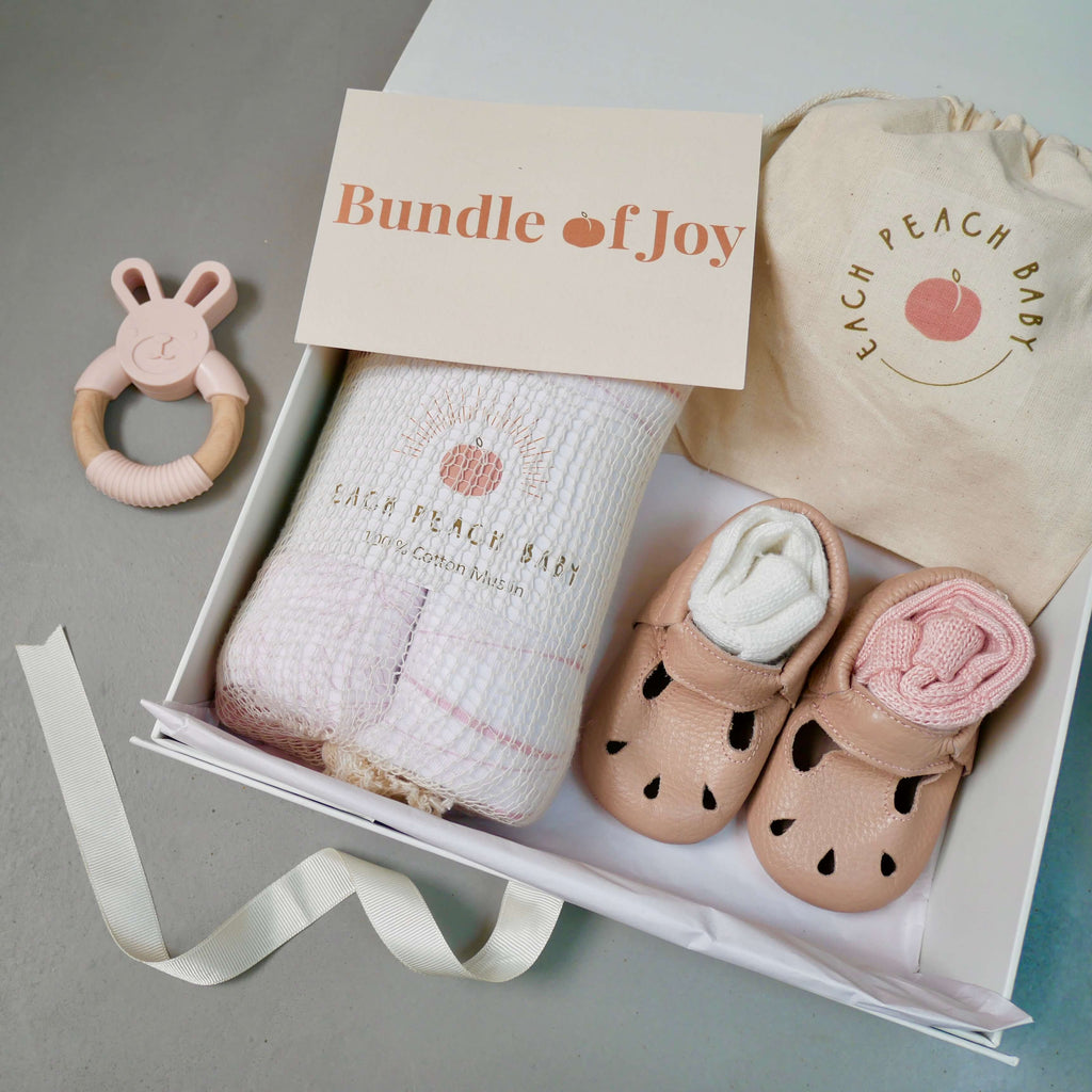 Newborn baby girl gift box set with Kit leather baby shoes in pink, organic muslin cloth set in pink, bamboo back socks in pick and ivory and a BPA-free eco-friendly teething toy in pink